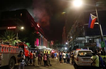 Evacuated employees and guests of hotels stand along a road and watch as smoke billows from a Resorts World building in Pasay City, Metro Manila, Philippines June 2, 2017. REUTERS/Erik De Castro