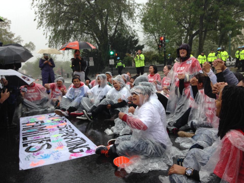 Demonstrators sit in the rain on Capitol Hill in Washington, Wednesday, April 30, 2014, during a protest calling for an end to deportations. Chanting protesters wore red shirts with the slogan “Stop Separating Families.” They locked arms and sat down in the street in the rain before Capitol Police rounded them up and loaded them in vans. (AP Photo/Luis Alonso)
