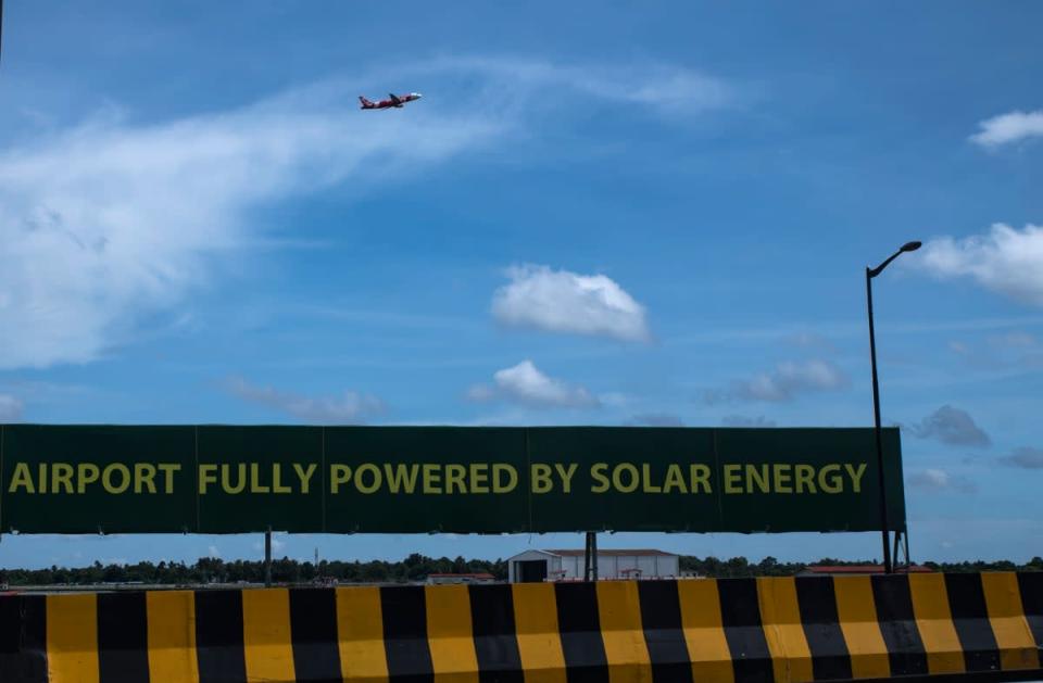 An aircraft takes off from the Cochin International Airport behind a signage that boasts of being world’s first airport powered by solar energy in Kerala state’s Kochi city on 25 August (AP)