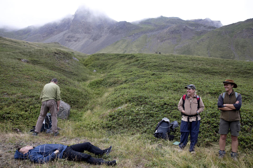 In this Saturday, Aug. 18, 2018, photo, Paula, right, and Sinead, second from right, of Australia, react as their North Korean guide takes a break during a hike arranged by Roger Shepherd of Hike Korea, top left, on Mount Paektu in North Korea. Hoping to open up a side of North Korea rarely seen by outsiders, Shepherd, a New Zealander who has extensive experience climbing the mountains of North and South Korea is leading the first group of foreign tourists allowed to trek off road and camp out under the stars on Mount Paektu, a huge volcano that straddles the border that separates China and North Korea. (AP Photo/Ng Han Guan)