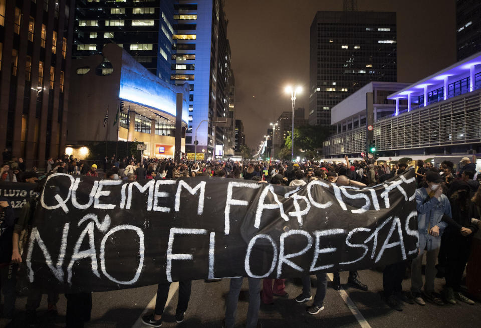 Demonstrators in Sao Paulo march holding a banner that reads in Portuguese: "Burn the fascists not the rainforest" (Picture: AP)