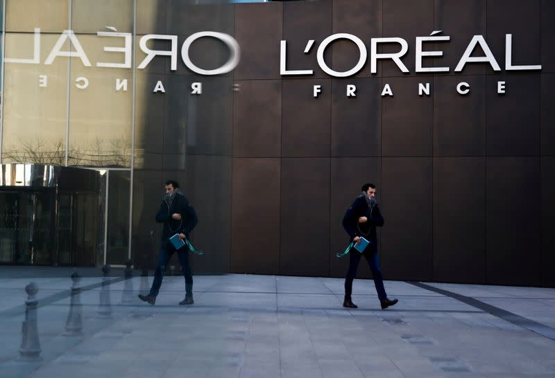 FILE PHOTO: A man walks by the logo of French cosmetics group L'Oreal in the western Paris suburb of Levallois-Perret