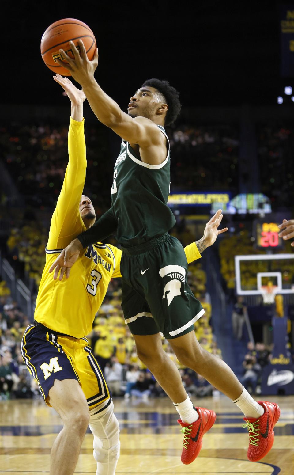 Michigan State guard Jaden Akins, right, goes to the basket against Michigan guard Jaelin Llewellyn (3) during the first half of an NCAA college basketball game Saturday, Feb. 17, 2024, in Ann Arbor, Mich. (AP Photo/Duane Burleson)