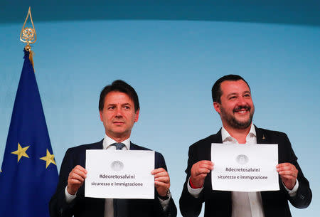 Italy's Prime Minister Giuseppe Conte and Interior Minister Matteo Salvini hold up pieces of paper with the name of the new decree written on them during a news conference at Chigi Palace in Rome, Italy, September 24, 2018. REUTERS/Alessandro Bianchi