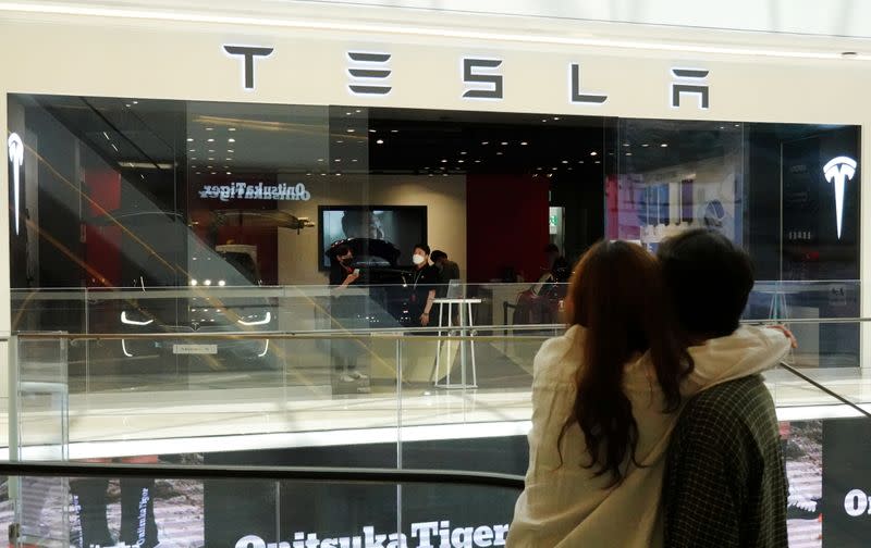 FILE PHOTO: A couple looks at a Tesla dealership in Hanam