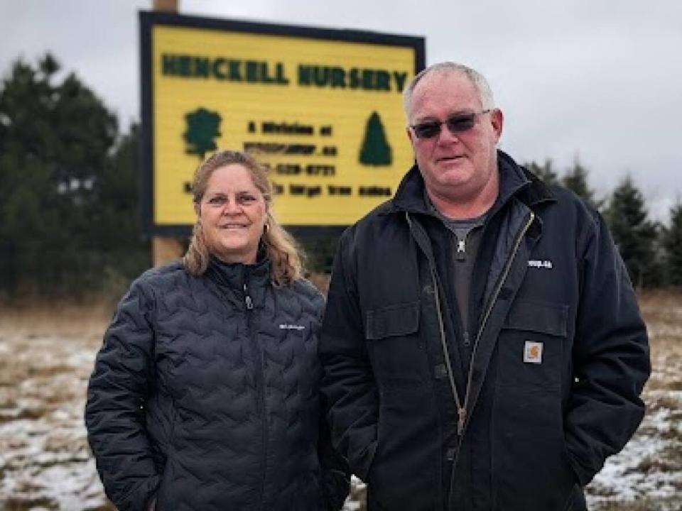 Della and Donald Wood stand in front of the sign at their tree nursery in Pownal, P.E.I.   (Shane Hennessey/CBC  - image credit)