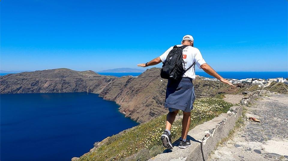 John Martin walking along the rocks in Santorini.