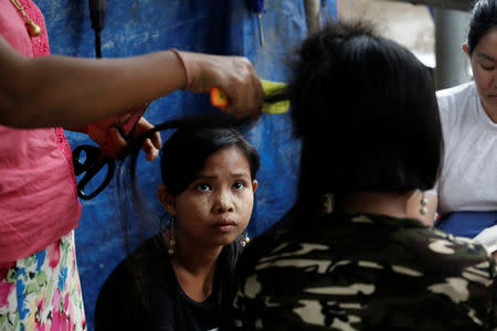 The sister of Za Za Lin watches as Za Za Lin, who sold her 20 inches hair for $16, gets her hair cut at Insein hair market in Yangon, Myanmar, June 18, 2018. Picture taken June 18, 2018. REUTERS/Ann Wang