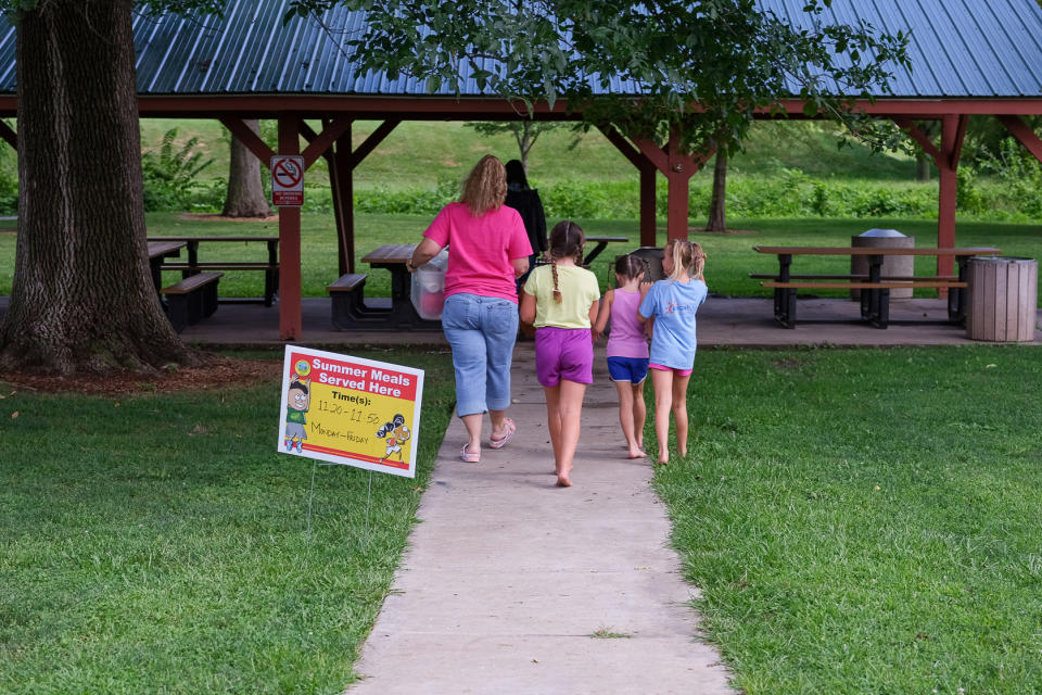 Image: Children follow as Christina Pinkerton and Shannon Bundridge take  food for the Summer Eats to the picnic area  in Kirksville, Mo., as on Aug. 16, 2022. (Arin Yoon for NBC News)