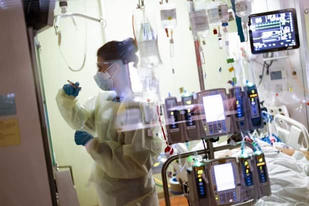 Nurse Ann Enderle attends to a COVID-19 patient in the medical intensive care unit (MICU) at St. Luke's Boise Medical Center in Boise, Idaho, on Aug. 31, 2021. There were only four open ICU beds available in all of Idaho at that time. So far, triage protocols have not had to be implemented.  (Kyle Green/AP - image credit)