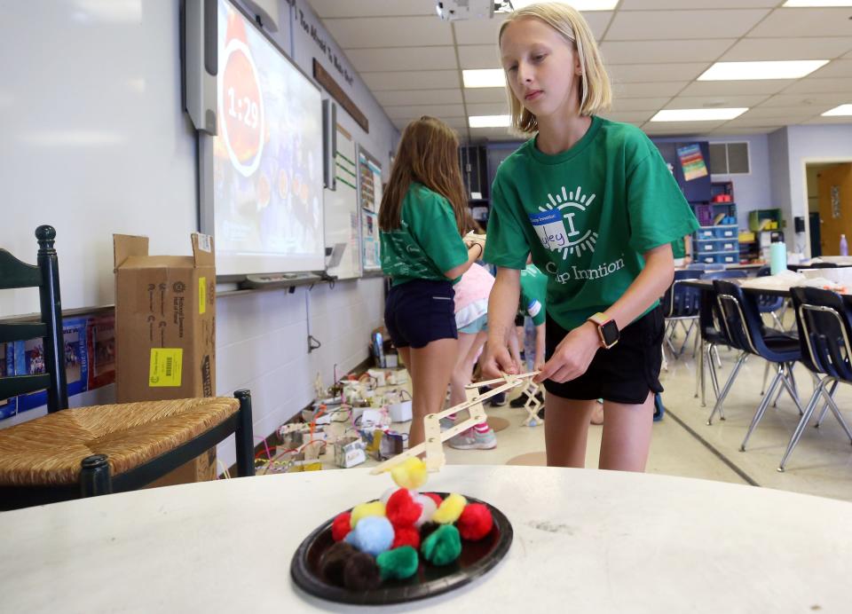 Liv Williamson, 10, uses her astro-arm to move the fuzzy balls, which represented pizza toppings, during a game June 9 at Grandview's Camp Invention 2022.