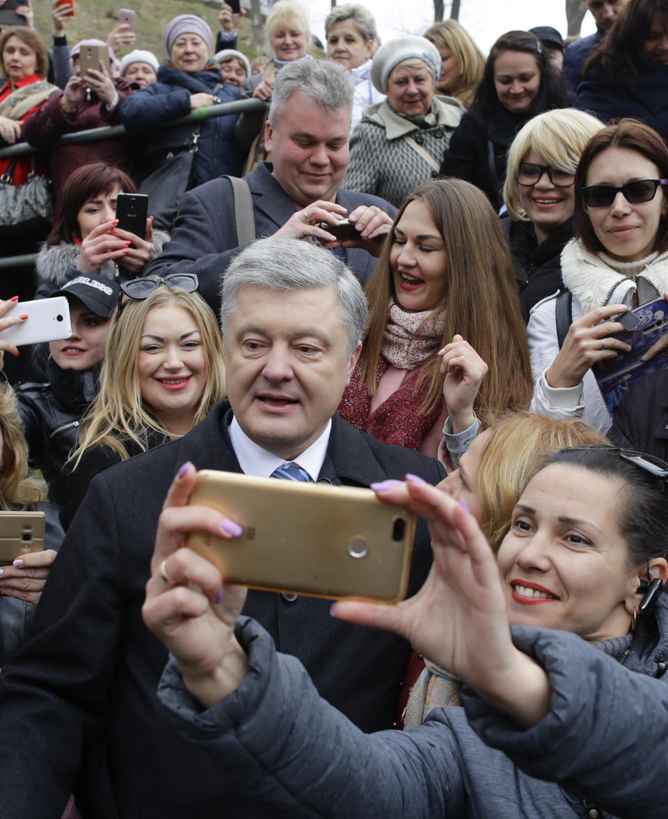 Ukrainian President Petro Poroshenko, center, poses for a selfie with a supporter after a public prayer ahead of Sunday's presidential election at the monument of Prince Volodymyr the Great Monument, the leader of Kievan Rus, in Kiev, Ukraine, Saturday, March 30, 2019. (AP Photo/Sergei Grits)