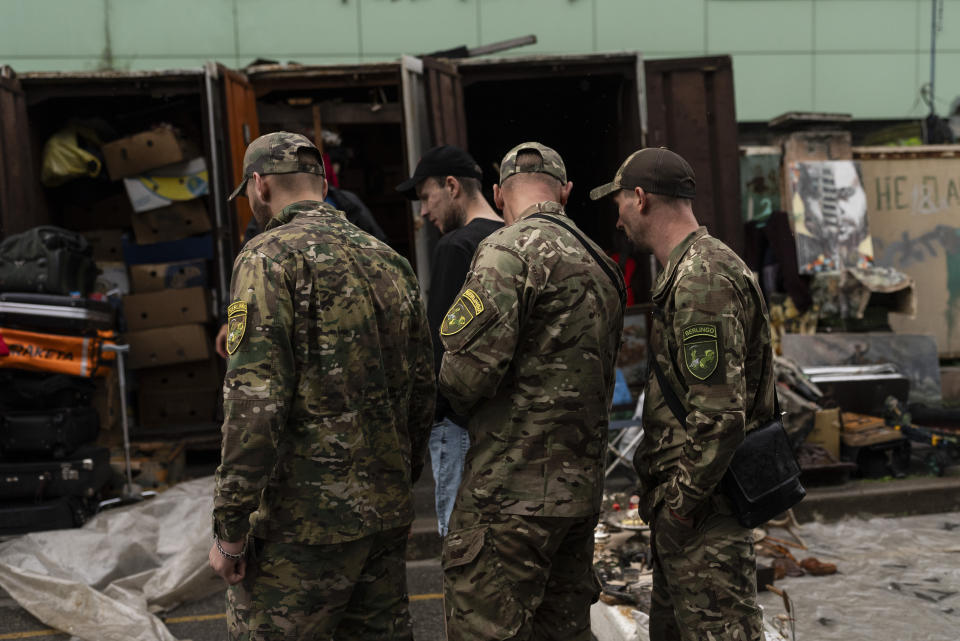 Tres soldados ucranianos se paran ante un puesto de un mercado callejero de Kiev, Ucrania, el 8 de julio de 2023. El vecindario de Pochaina de la capital ucraniana cobra vida cada fin de semana cuando cientos de personas acuden en masa a su famoso mercadillo en busca de tesoros. (AP Foto/Jae C. Hong)