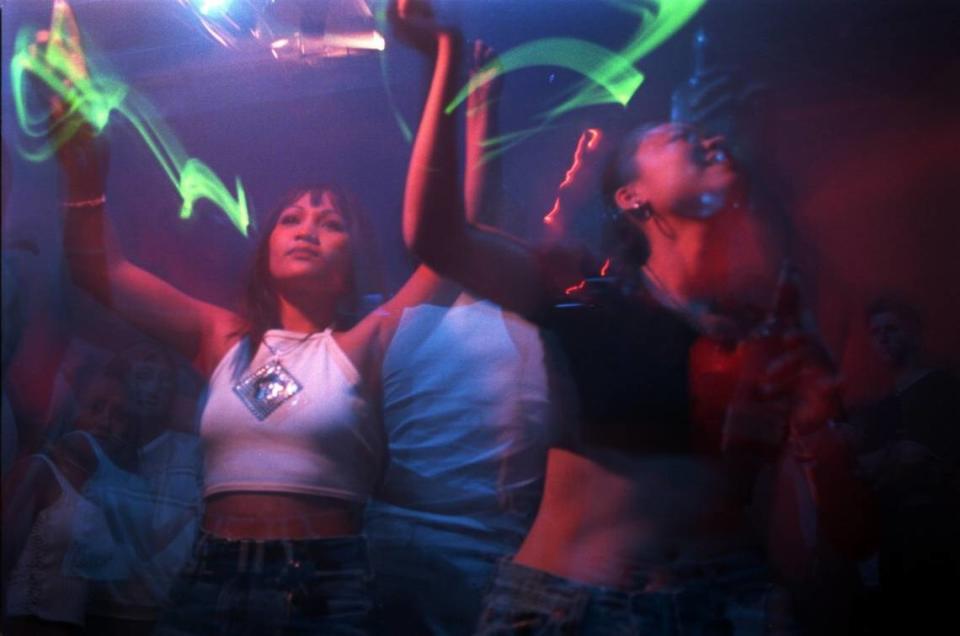 Khio Senensom, left, dances with a glow stick with her friend Lil Lee late night as DJ Andy K spins his house music at Mythos dance club in August 1999.