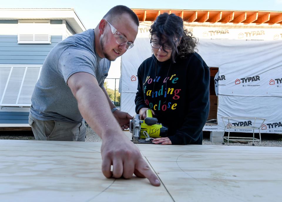 Micha Kelley, the tiny home constructor at Project LIFT, helps guide Gabriella Torres, 14, of Port St. Lucie, with using a circular saw for a project at the Project LIFT offices on Tuesday, Nov. 23, 2021, in Palm City. "I'm the tiny home constructor we work on everything to do with construction, building these two tiny homes out here," Kelley said. "Everything from start to finish. I'm really thankful to be here, growing up unfortunate myself, I'm glad to help others out so that they can get ahead in life."