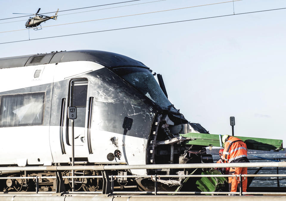 Rescue workers at the site of a train accident on Great Belt Bridge in Nyborg, in Denmark, Wednesday, Jan. 2, 2019. At least six people were killed and 16 others injured early Wednesday when a Danish passenger train apparently hit falling cargo from a passing freight train as it crossed a bridge linking central Denmark's islands. Police spokesman Lars Braemhoej said that while "we do not know precisely what caused the accident," one possible cause was that cargo from a passing freight train fell off and hit the passenger train. He added there was "considerable damage" on the passenger train. (Tim Kildeborg Jensen/Ritzau Scanpix via AP)