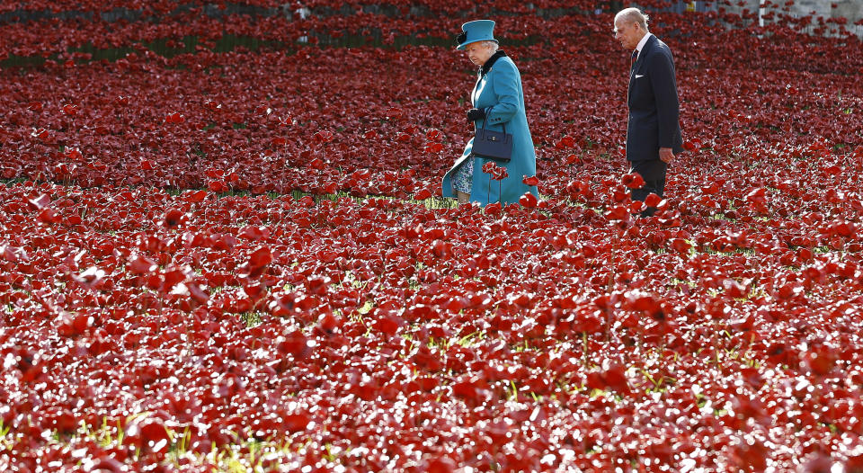 FILE - In this Oct. 16, 2014 file photo Britain's Queen Elizabeth II, left, and Prince Philip walk through the field of ceramic poppies at The Tower of London. The 99-year-old husband of Queen Elizabeth II has been hospitalized after a heart procedure. Prince Philip, the irascible and tough-minded husband of Queen Elizabeth II who spent more than seven decades supporting his wife in a role that both defined and constricted his life, has died, Buckingham Palace said Friday. He was 99. (AP Photo/Kirsty Wigglesworth, File)