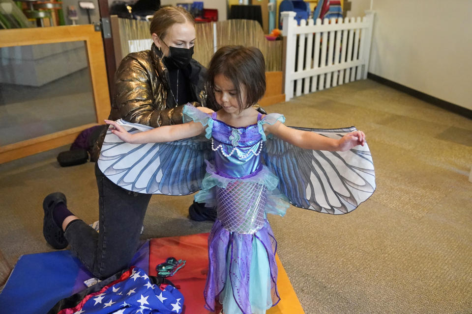 Angela Montierth helps her daughter Justina, 4, with her costume during a visit to Discovery Gateway Children's Museum Thursday, Oct. 28, 2021, in Salt Lake City. Coronavirus cases in the U.S. are on the decline, and trick-or-treaters can feel safer collecting candy. (AP Photo/Rick Bowmer)