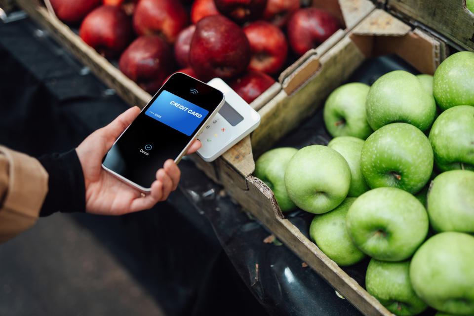 A person using a credit card to buy produce.