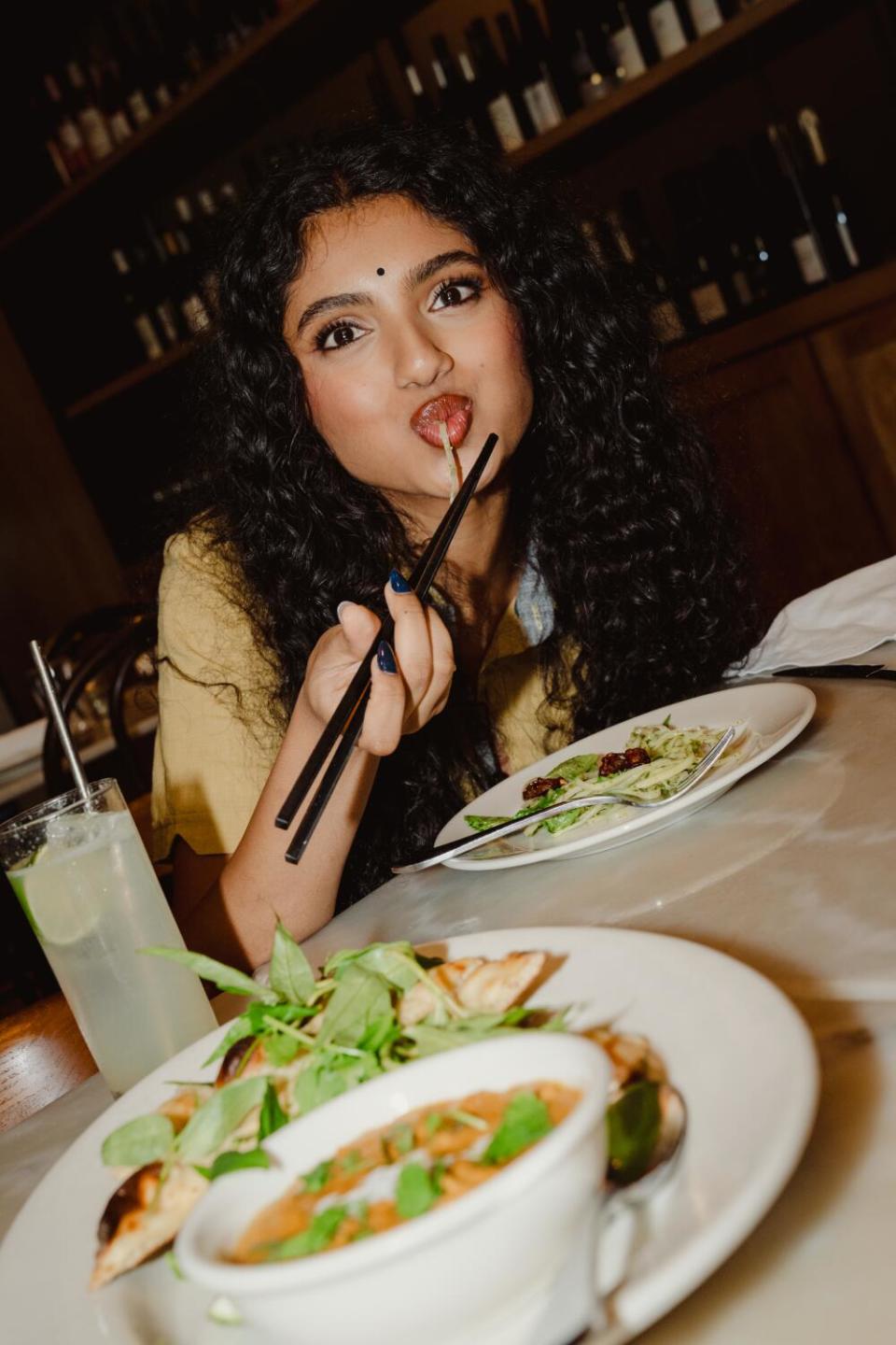 Avantika eats papaya salad with chopsticks at Cassia in Santa Monica