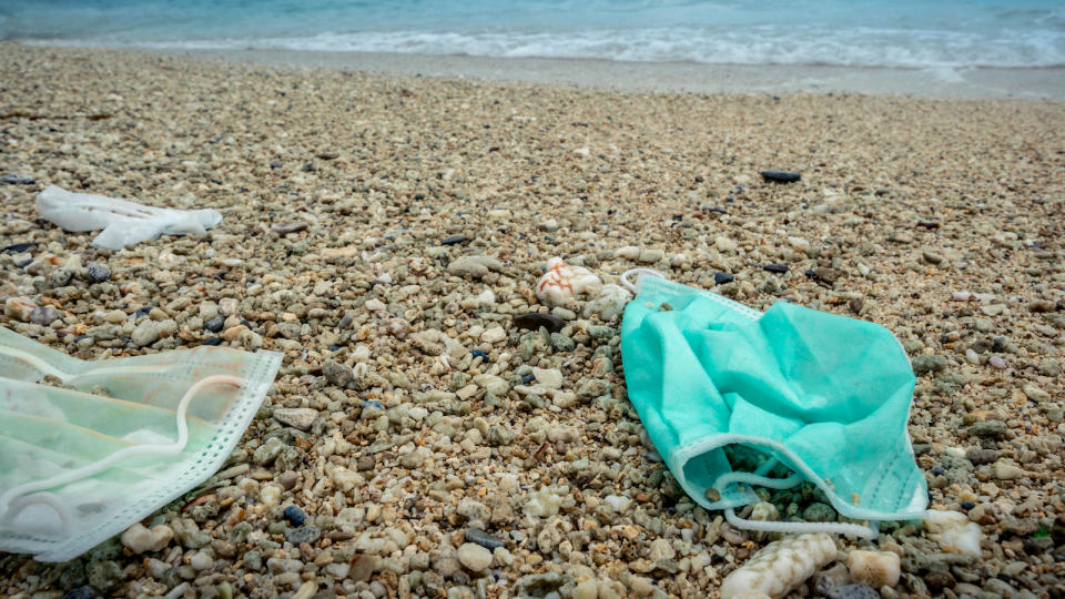 The waves washed up old used medical mask waste.