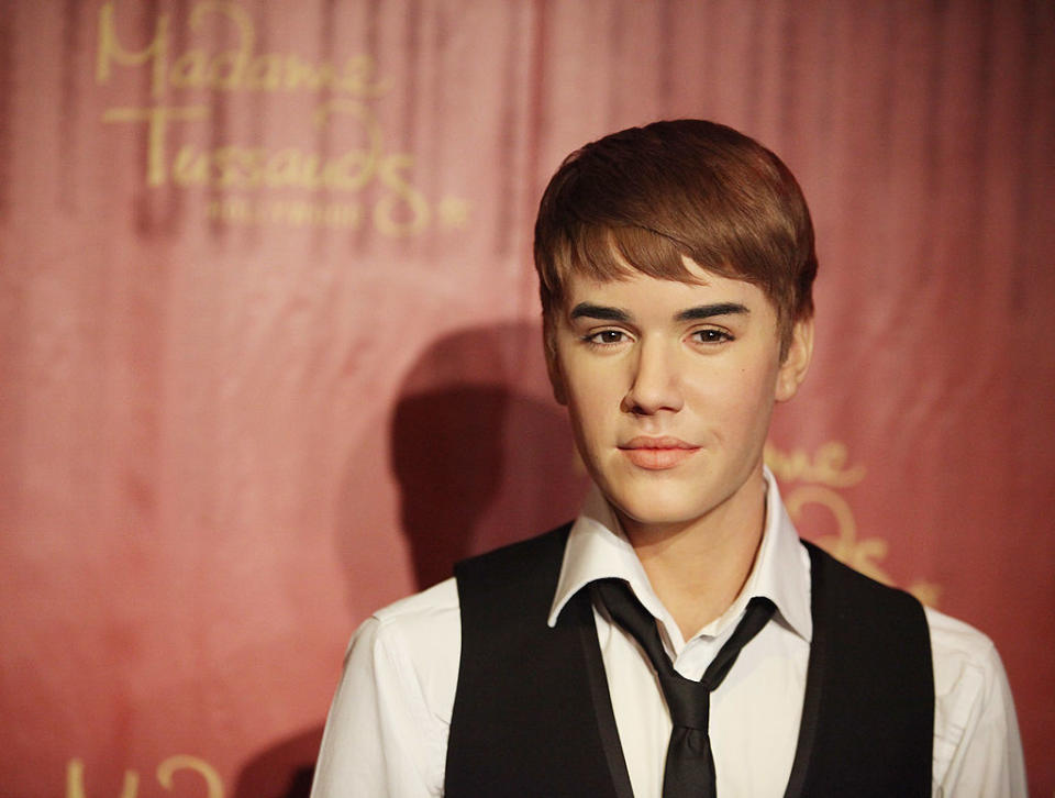 Wax figure of Justin Bieber wearing a black vest, white shirt, and black tie