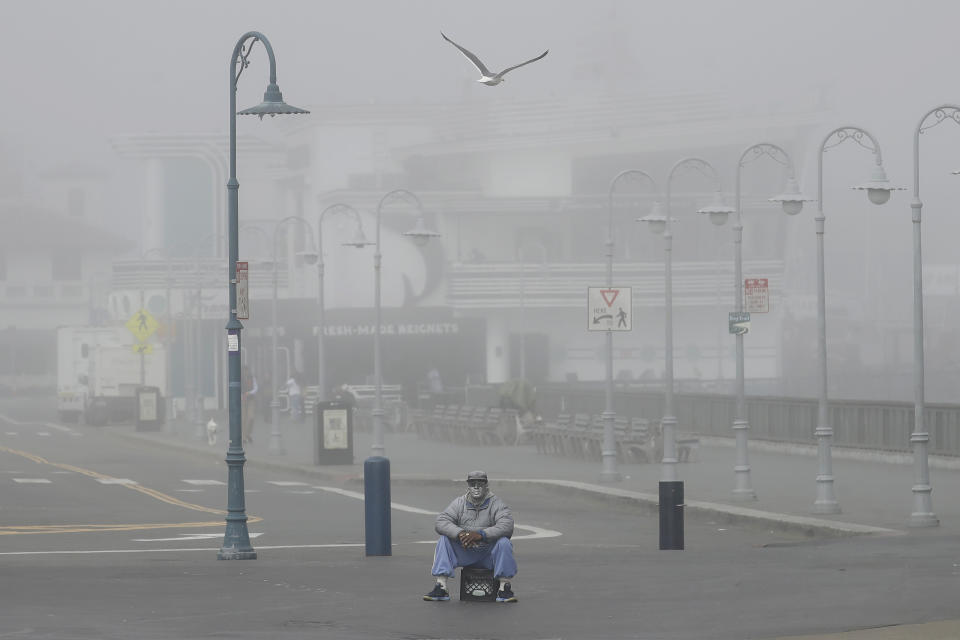 A street performer sits alone at Fisherman's Wharf in San Francisco, Thursday, March 12, 2020. California Gov. Gavin Newsom said Thursday that sweeping guidance for Californians to avoid unnecessary gatherings to avoid the spread of the new coronavirus will likely extend beyond March. The statewide guidance applies to sporting events, concerts and even smaller social gatherings in places where people can't remain at least 6 feet (2 meters) apart. For most people, the new coronavirus causes only mild or moderate symptoms. For some it can cause more severe illness. (AP Photo/Jeff Chiu)