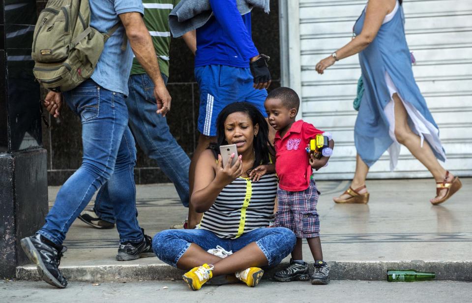 In this Jan. 6, 2017 photo a woman with her child uses a public wifi hotspot in Havana, Cuba. While the island nation remains one of the world’s least internet-connected societies, ordinary citizens’ access to the internet has exploded over the last two years. (AP Photo/Desmond Boylan)