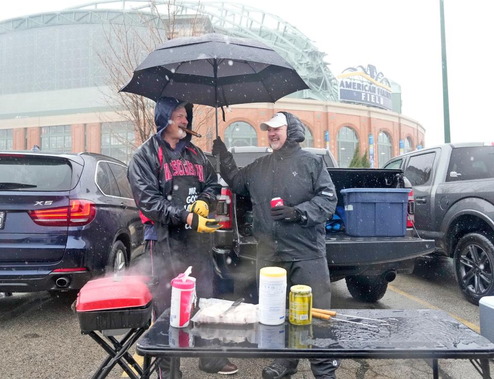 Mark Langworthy (left) of Middleton gets a little help with an umbrella from Larry Rasmussen, of Madison as the rain comes down before the Milwaukee Brewers home opener against the Minnesota Twins at American Family Field in Milwaukee on Tuesday, April 2, 2024.