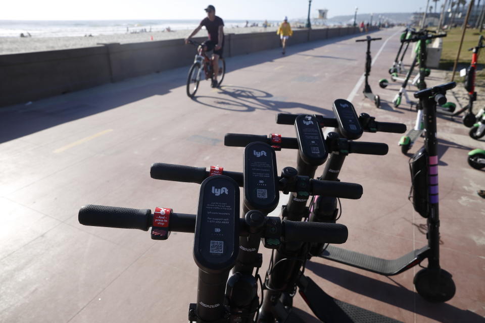 FILE - In this May 28, 2019, file photo Lyft scooters are seen along Mission Beach boardwalk in San Diego. San Diego is suing scooter companies to get them to pay the city's costs to defend any lawsuits generated by the two-wheeled vehicles that have proliferated on public sidewalks. (AP Photo/Gregory Bull, File)