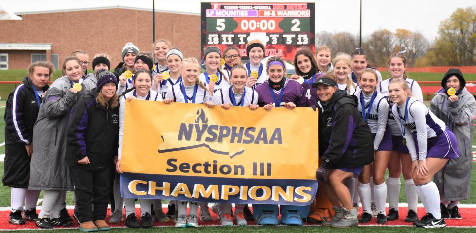 The Little Falls Mounties pose with their championship banner after winning Section III's Class D field hockey final Sunday.