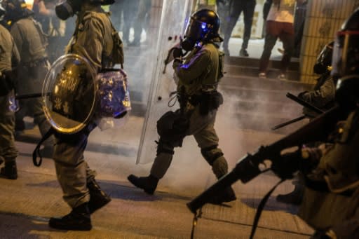 Riot police walk through clouds of tear gas fired at protesters in Hong Kong