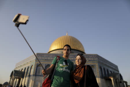 Palestinian Muhamad Etmezeh, 26, from the West Bank village of Idna, near Hebron, takes a selfie photo with his wife in front of the Dome of the Rock on the compound known to Muslims as Noble Sanctuary and to Jews as Temple Mount, in Jerusalem's Old City, during the holy month of Ramadan, July 1, 2015. REUTERS/Ammar Awad