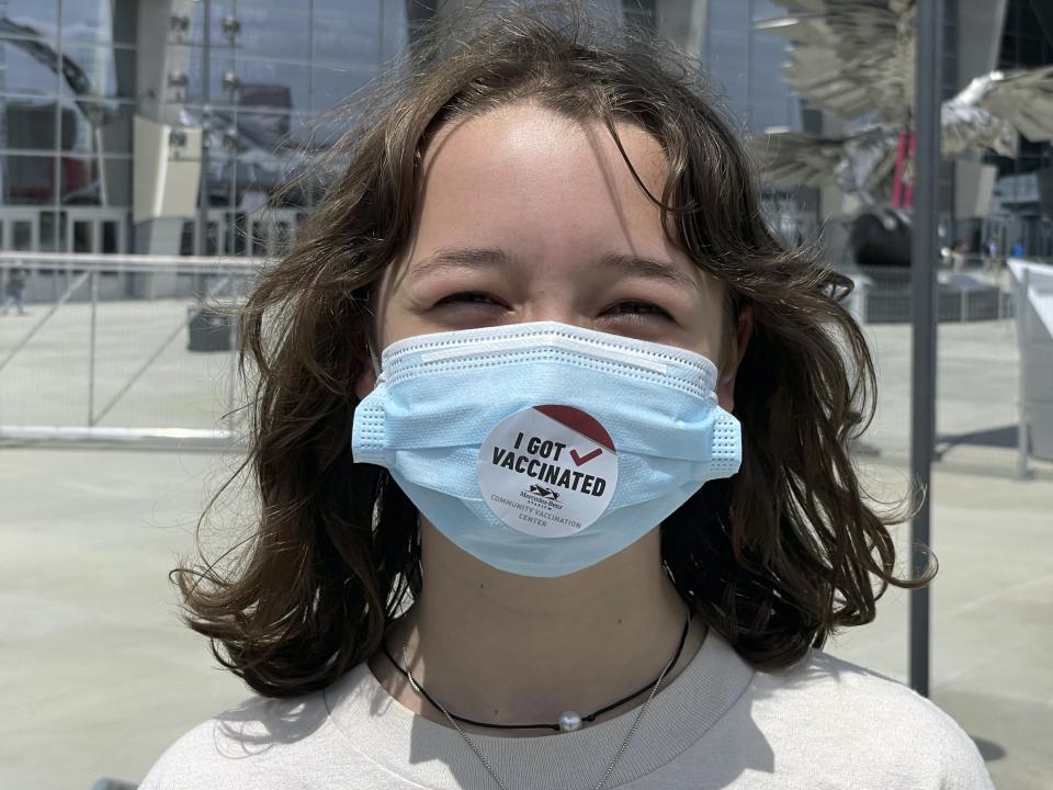 Une jeune fille portant un masque où il est écrit qu’elle a été vaccinée