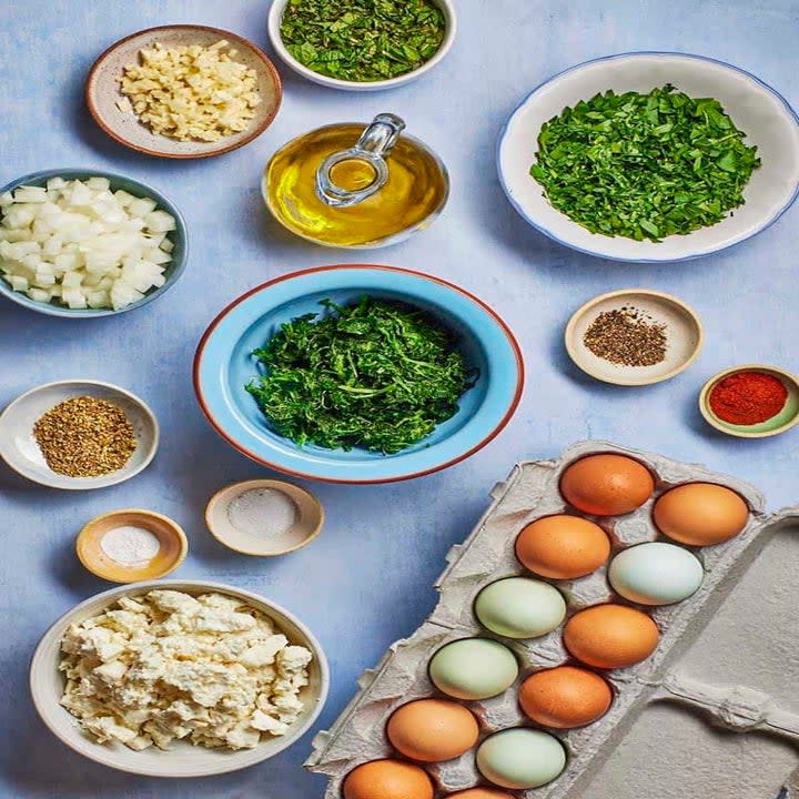 ingredients for spanakopita egg muffins on a blue counter