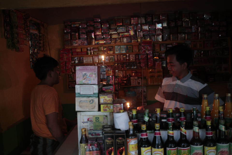 A vendor lights candles at his herbal drink stall during a power outage in Jakarta, Indonesia, Sunday, Aug. 4, 2019. Indonesia's sprawling capital and other parts of Java island have been hit by a massive power outage affecting millions of people. (AP Photo/Dita Alangkara)