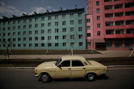 FILE PHOTO: A car drives past residential buildings in Pyongyang April 11, 2012. REUTERS/Bobby Yip/File Photo