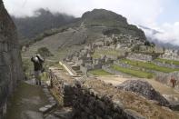 A maintenance worker carries a bag of stones at the Machu Picchu archeological site that's closed to the public amid the COVID-19 pandemic in the department of Cusco, Peru, Tuesday, Oct. 27, 2020. The world-renown Incan citadel of Machu Picchu will reopen to the public on Nov. 1. (AP Photo/Martin Mejia)