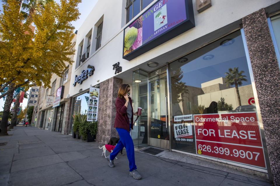 A pedestrian walks dogs past a closed business on Colorado Boulevard in Pasadena