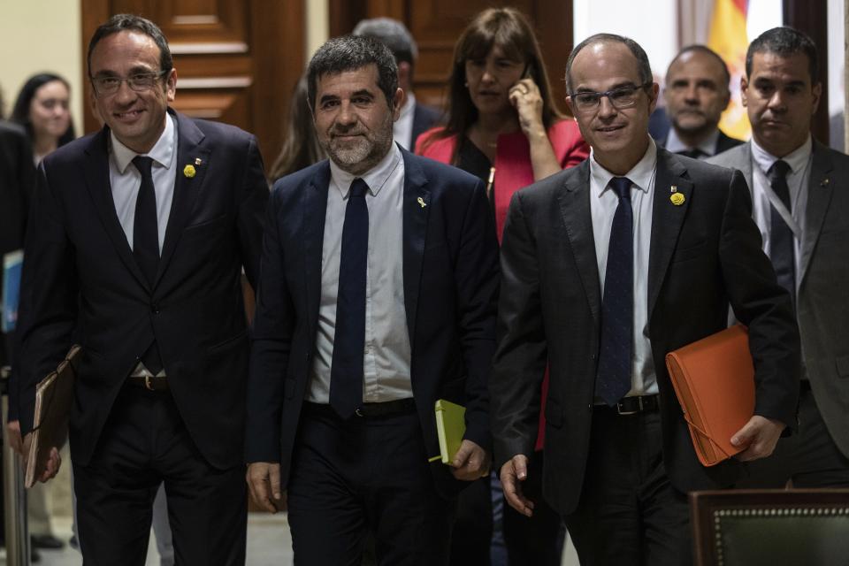 Catalan politicians Josep Rull, left, Jordi Sanchez and Jordi Turull, right, leave after collecting their credentials at the Spanish parliament in Madrid, Spain, Monday, May 20, 2019. The five separatist leaders on trial for Catalonia's 2017 secession attempt who were elected to the Spanish Parliament in April 28 elections have been escorted by police to pick up their official credentials. The five, along with other defendants, are being held in pre-trial jail. They face several years in prison if found guilty of rebellion. (AP Photo/Bernat Armangue)