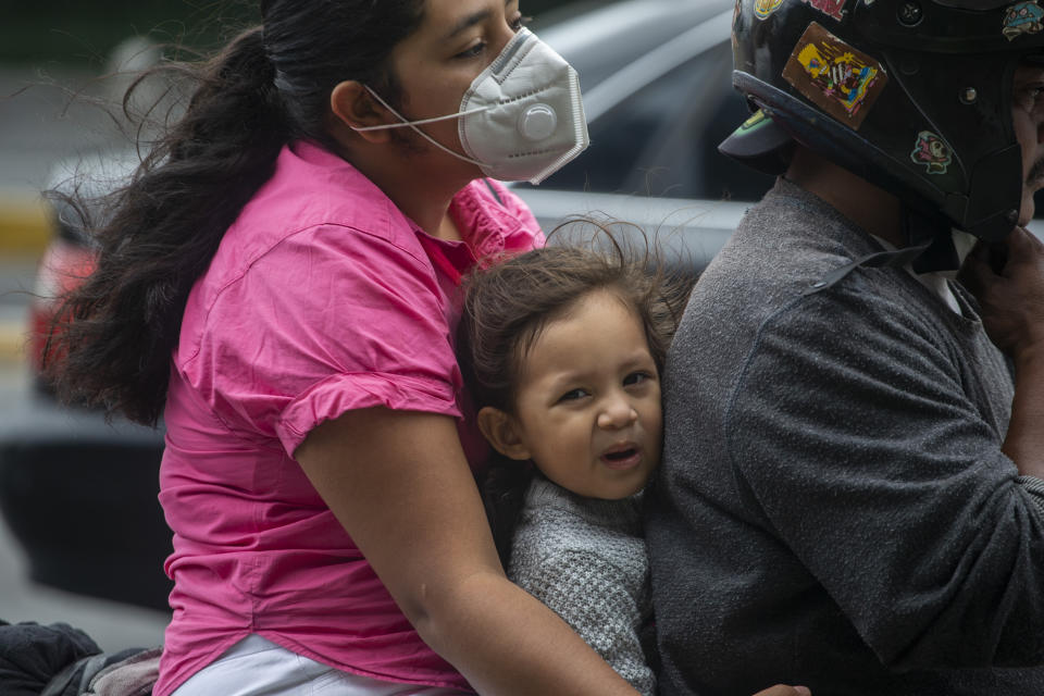 A family rides a motorcycle past a checkpoint during the first day of a system limiting the days that vehicles can go out as a way to curb the spread of COVID-19, ordered by the government for the metropolitan area of Guatemala City, Tuesday, June 16, 2020. (AP Photo/Moises Castillo)