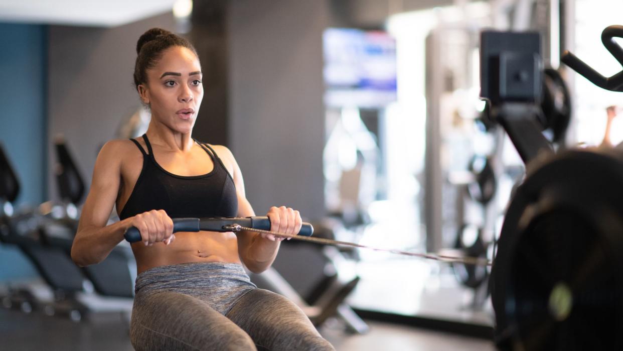  Woman doing a rowing machine workout as an alternative to running. 