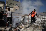 A firefighter drags a hose to the site of a destroyed house in Rafah in the south of the Gaza Strip on August 20, 2014, targeted late the night before in an Israeli airstrike