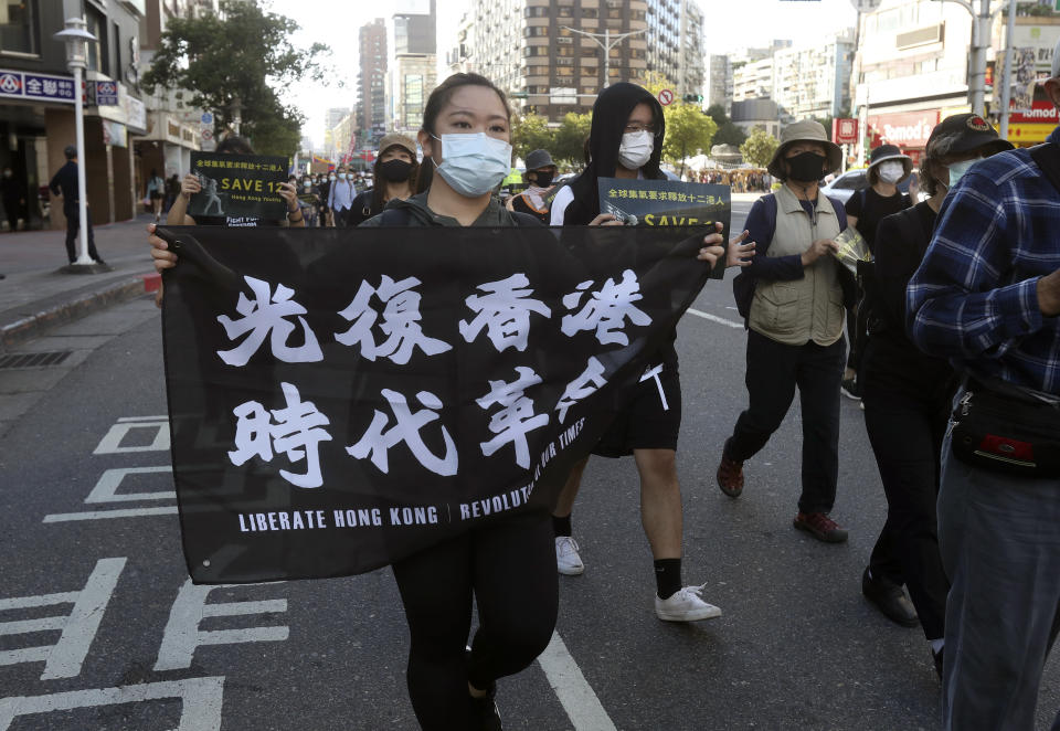 A protester holds a slogan "Liberate Hong Kong" during a march to demand the release of the 12 Hong Kong protesters that have been arrested by mainland Chinese authorities, in Taipei, Taiwan, Sunday, Oct. 25, 2020. A group of 12 people from Hong Kong were allegedly traveling illegally by boat to Taiwan in August when Chinese authorities captured them and detained them. (AP Photo/Chiang Ying-ying)