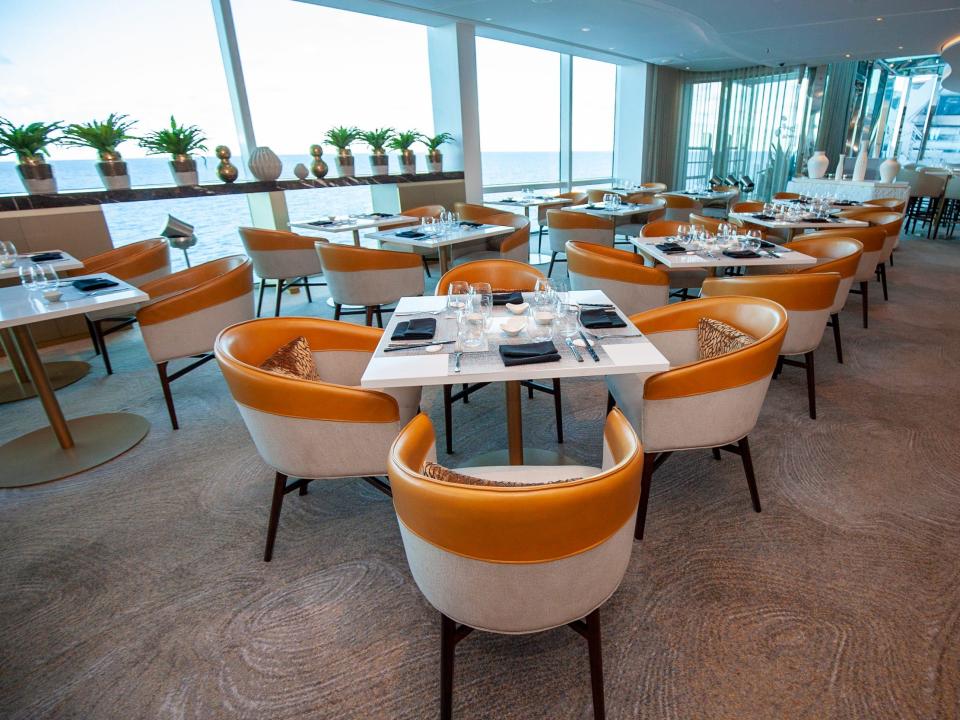 an empty restaurant by windows showing the ocean