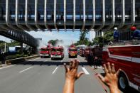 A firefighter gestures to fellow firefighters to stop spraying disinfectant in order to refill their tanks, as the disinfectant is integral in the prevention of the spread of the coronavirus disease (COVID-19), on the main road in Jakarta