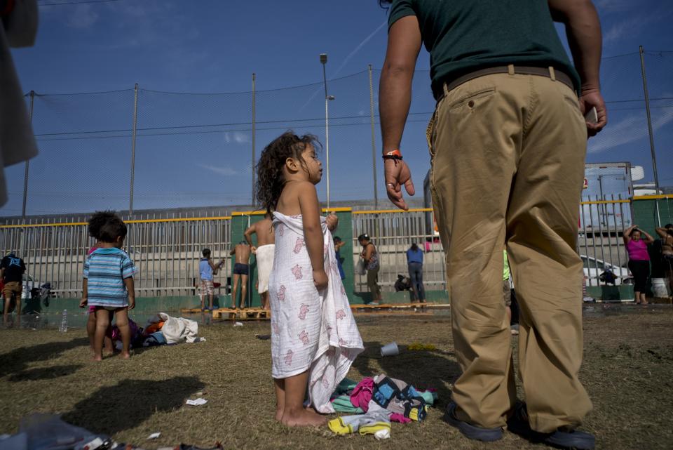 A girl, part of the migrant caravan, talks with her father after taking a bath at a shelter in Tijuana, Mexico, Wednesday, Nov. 21, 2018. Migrants camped in Tijuana after traveling in a caravan to reach the U.S are weighing their options after a U.S. court blocked President Donald Trump's asylum ban for illegal border crossers. (AP Photo/Ramon Espinosa)