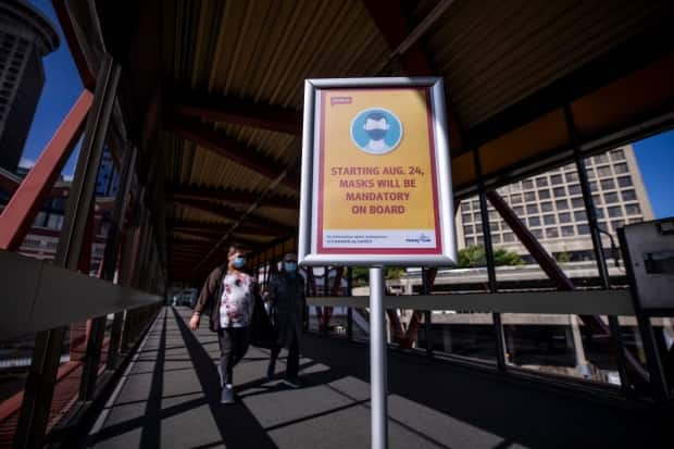 A TransLink sign reminding passengers about mandatory masks is pictured in August 2020. Police say a woman was attacked on a SkyTrain in Burnaby, B.C., on Monday after asking two other passengers if they had masks to wear. (Ben Nelms/CBC - image credit)