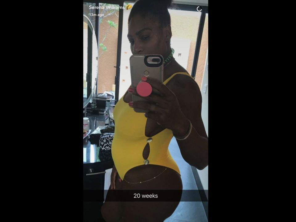 Serena Williams in a yellow swimsuit showing off her baby bump in the mirror.