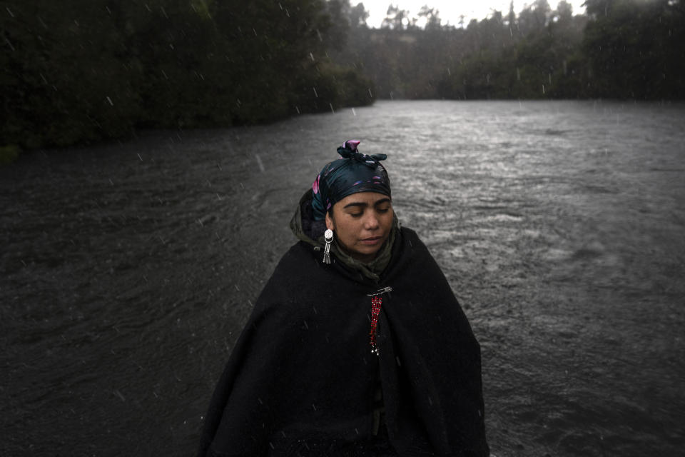 Millaray Huichalaf, a Mapuche machi, or healer and spiritual guide, rides in a boat on the Pilmaiquen River in Los Rios, southern Chile, on Tuesday, July 12, 2022. During years of training to become a machi, she started having dreams about Kintuantü, a ngen, or protector spirit, living by a broad bend of the Pilmaiquen. "Through dreams and visions in trance, Kintuantü told me that I had to speak for him because he was dying," Huichalaf says. (AP Photo/Rodrigo Abd)